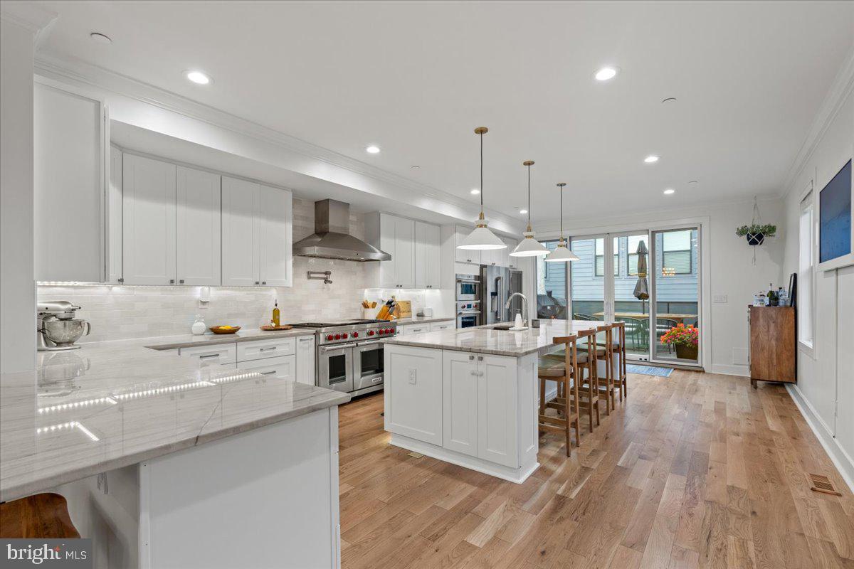 3424 Toone Street Baltimore, MD 21224 - Photo 58 of 87 a kitchen with stainless steel appliances kitchen island granite countertop a stove a sink a refrigerator and white cabinets with wooden floor