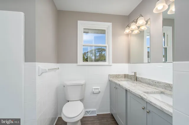 a bathroom with a granite countertop toilet sink and mirror
