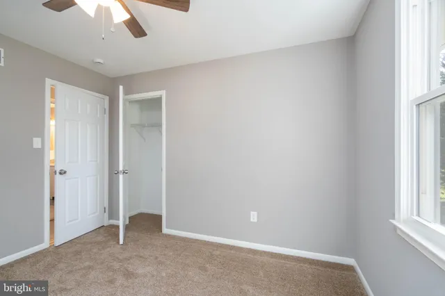 an empty room with a window and chandelier fan