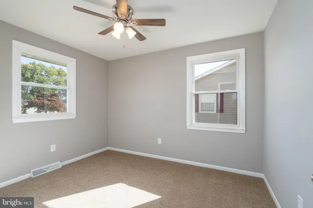 an empty room with a window and a fan