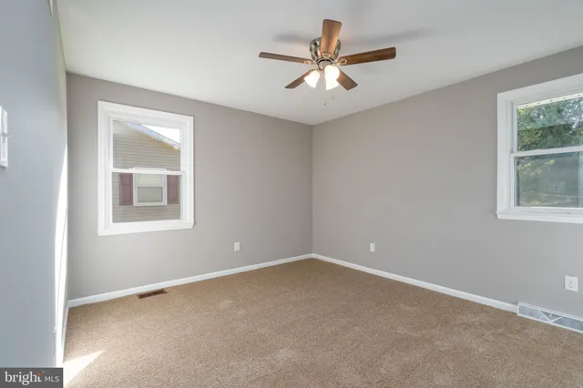 an empty room with a window and a fan