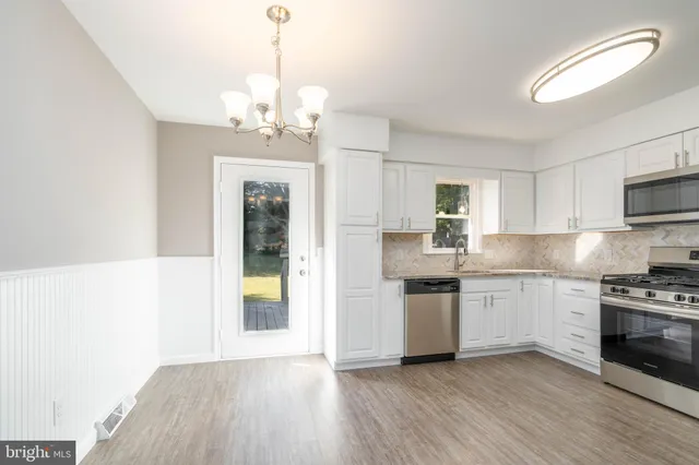 a kitchen with stainless steel appliances granite countertop a stove top oven a sink dishwasher and a refrigerator with wooden floor