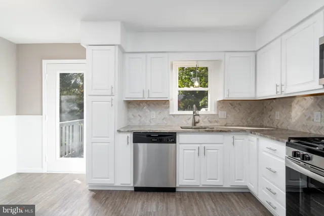 a kitchen with granite countertop white cabinets and a stove with wooden floor