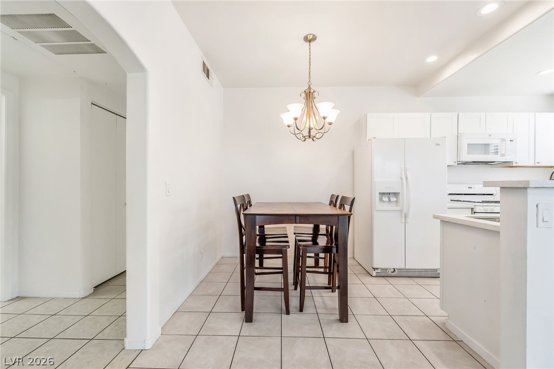 2201 Ramsgate Drive, Unit 811 Henderson, NV 89074 - Photo 7 of 36 A well-lit kitchen and dining area features tile flooring and a classic chandelier.