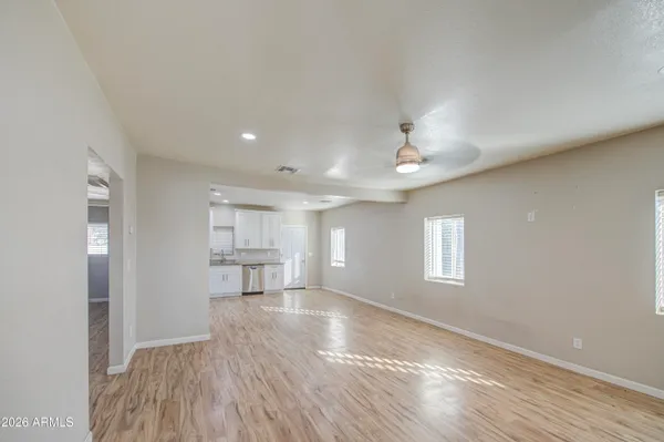 a view of a kitchen and empty room with wooden floor