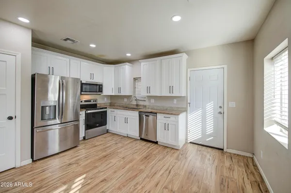 a kitchen with granite countertop white cabinets and stainless steel appliances