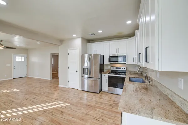 a kitchen with stainless steel appliances granite countertop a refrigerator a stove and a sink