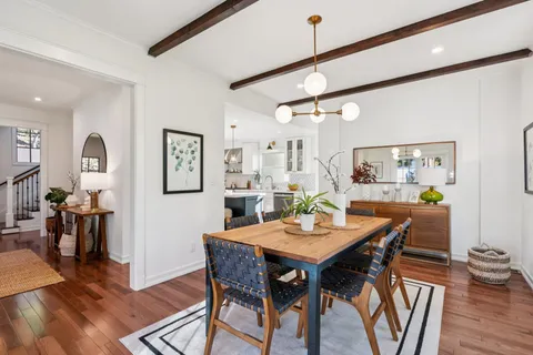 a view of a dining room and livingroom with furniture wooden floor a rug a flat screen tv