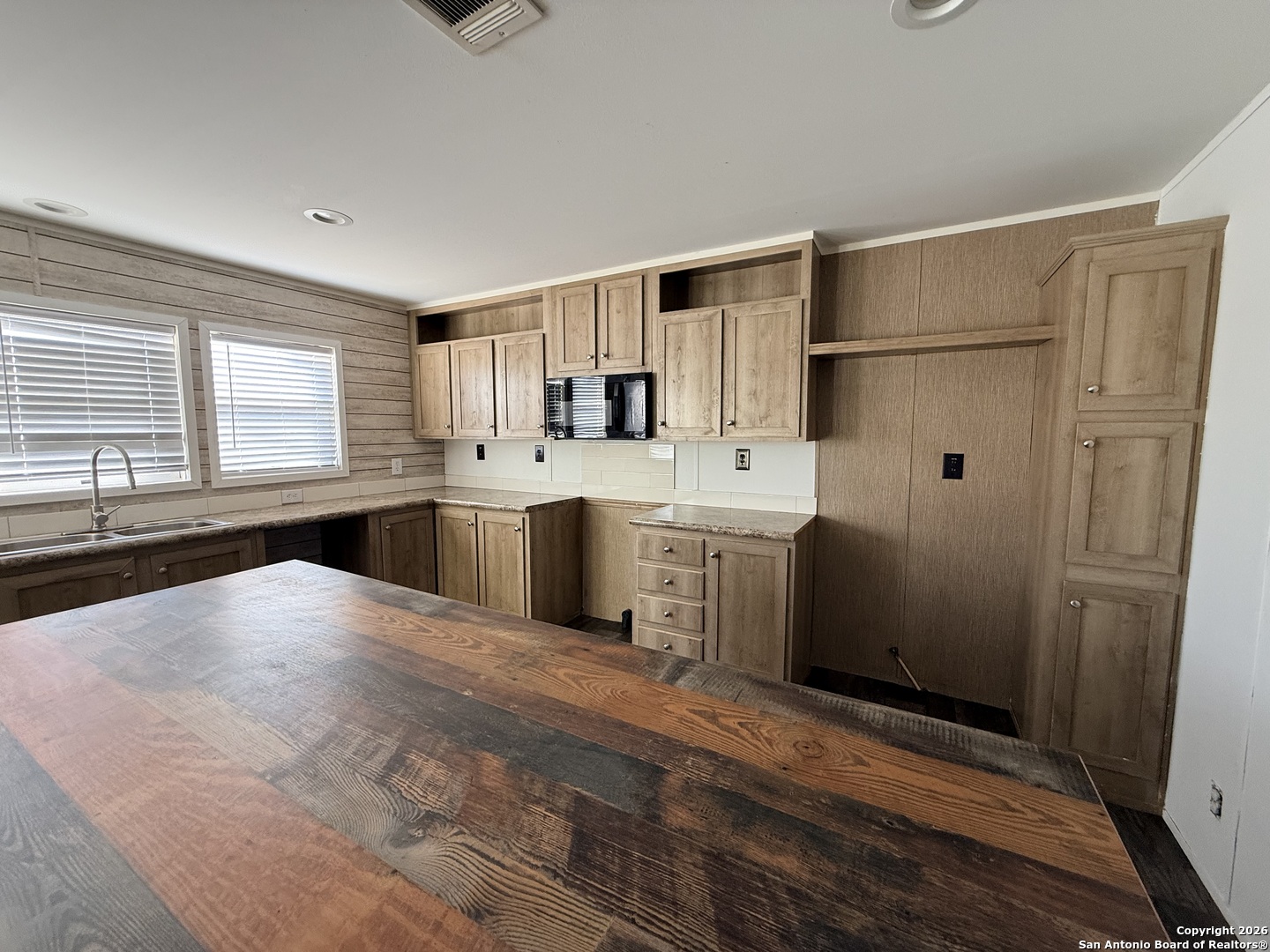 1009 County Road 773 Devine, TX 78016 - Photo 7 of 15 a large kitchen with a refrigerator a sink dishwasher a stove and white cabinets with wooden floor