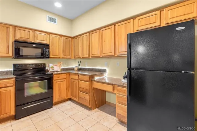 a kitchen with stainless steel appliances granite countertop a refrigerator a stove a sink and a microwave