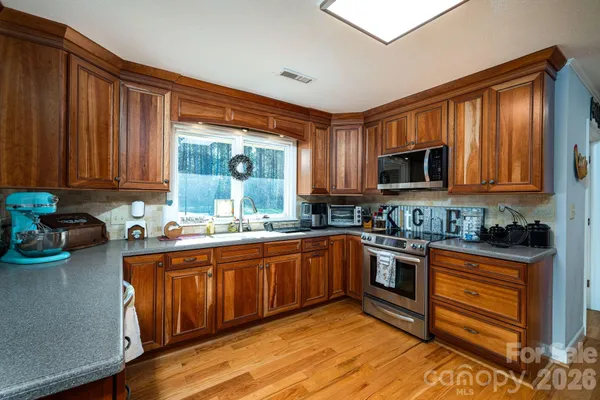 a open kitchen with stainless steel appliances granite countertop a stove a sink dishwasher and cabinets with wooden floor
