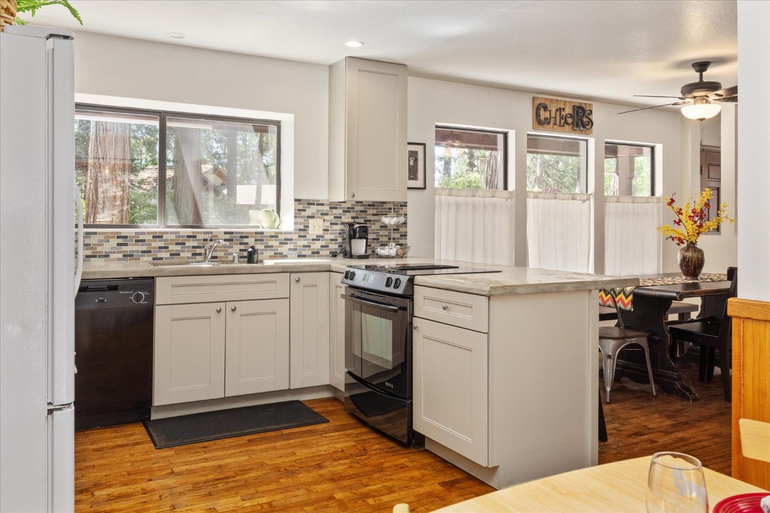 680 Larkspur Lane Murphys, CA 95247 - Photo 17 of 41 a kitchen with a stove a sink and white cabinets with wooden floors