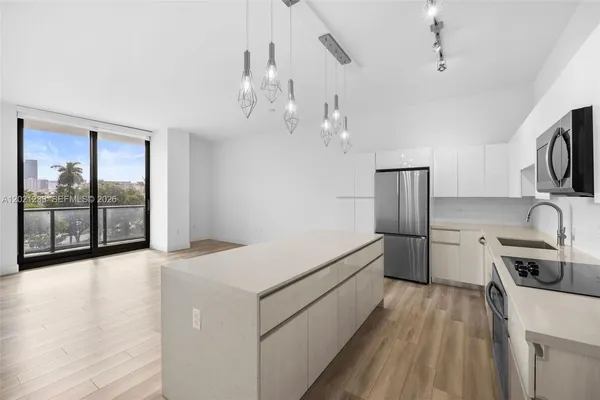 a view of a kitchen with a sink wooden cabinets and stainless steel appliances
