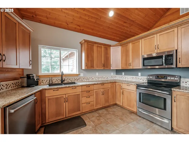 a kitchen with stainless steel appliances granite countertop a stove sink microwave and window