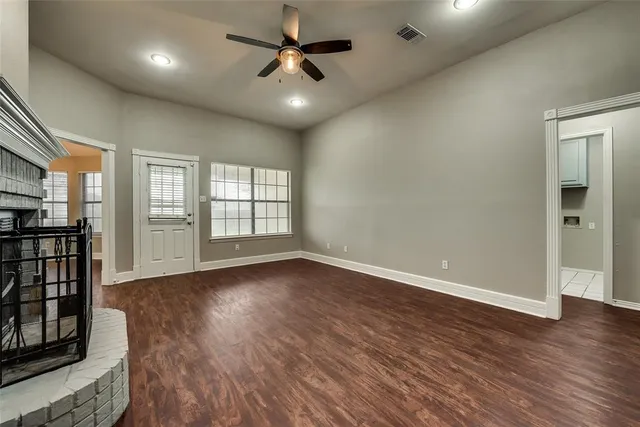 an empty room with wooden floor fan and windows
