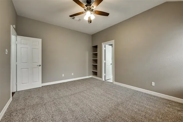 an empty room with closet and a chandelier fan