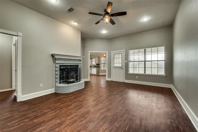 an empty room with wooden floor fireplace and windows