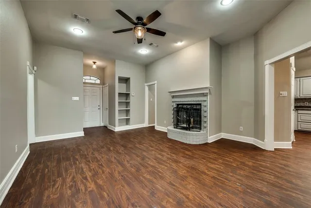an empty room with wooden floor fireplace and windows