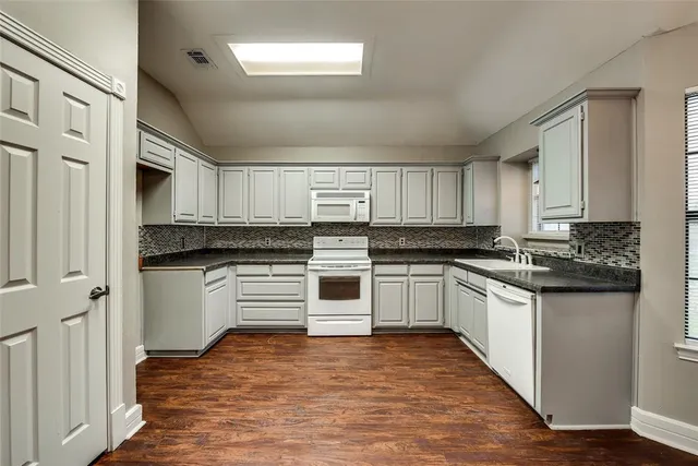 a kitchen with granite countertop a refrigerator and white cabinets
