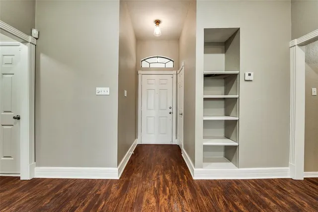 a view of a hallway with wooden floor and cabinet