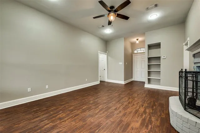 an empty room with wooden floor and a ceiling fan