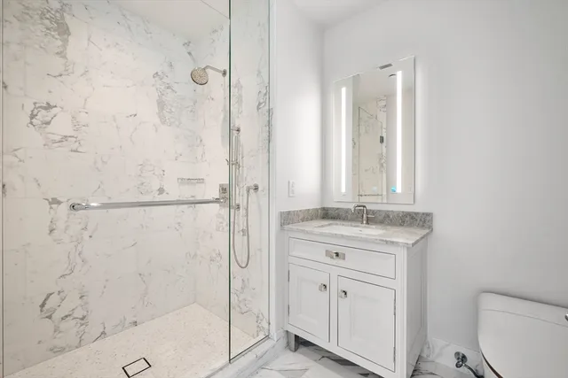 a bathroom with a granite countertop sink a toilet and shower