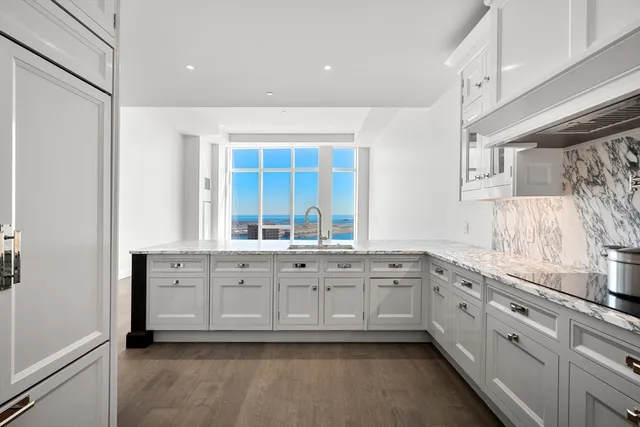 a large white kitchen with stainless steel appliances granite countertop a sink and a window