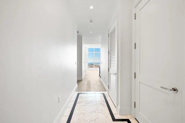 a view of a hallway with wooden floor and a bathroom