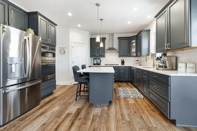 a kitchen with stainless steel appliances a refrigerator a sink dishwasher a stove and white cabinets with wooden floor