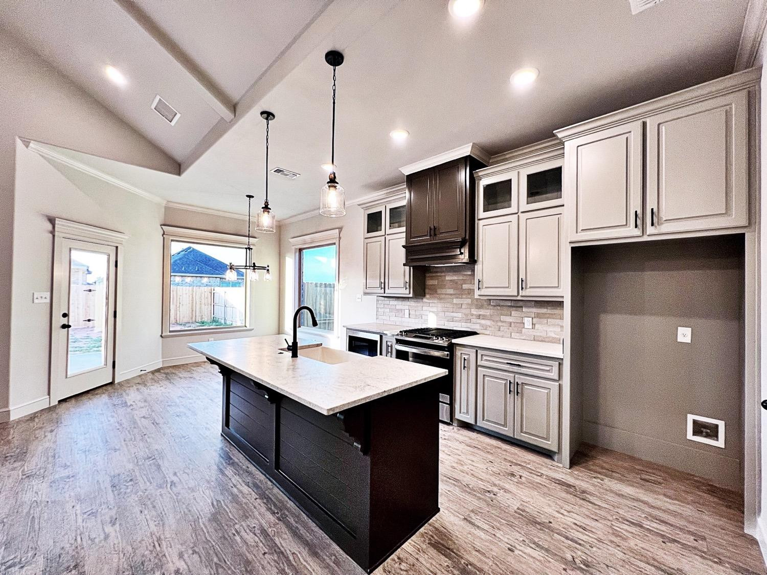 6920 17th Street Lubbock, TX 79416 - Photo 11 of 34 a kitchen with stainless steel appliances granite countertop a sink stove and wooden cabinets