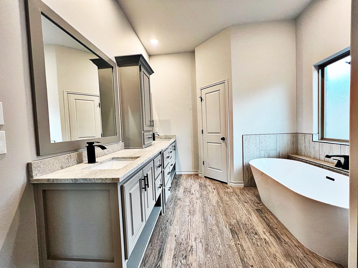 6920 17th Street Lubbock, TX 79416 - Photo 19 of 34 a bathroom with a tub sink and mirror