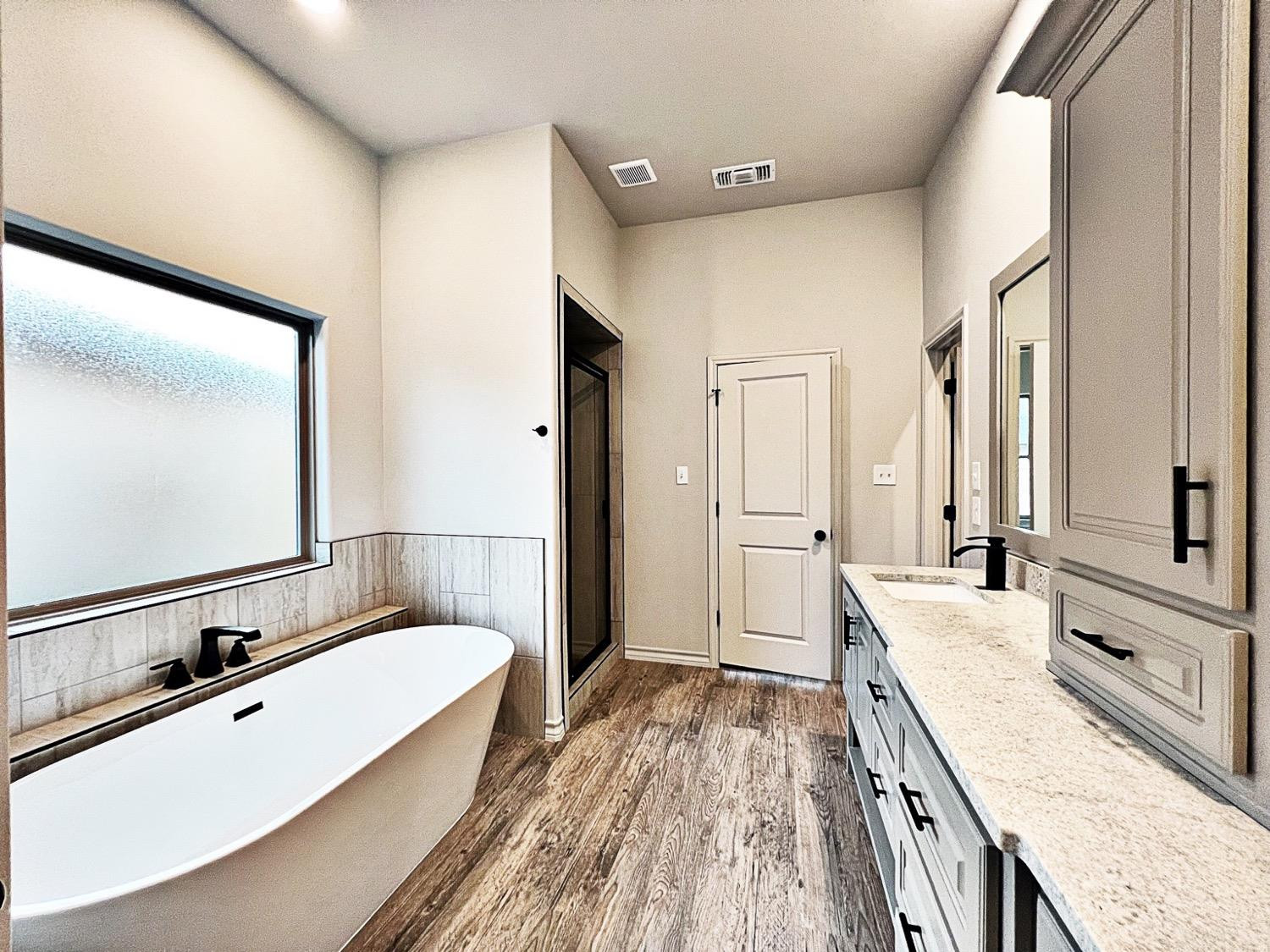 6920 17th Street Lubbock, TX 79416 - Photo 20 of 34 a spacious bathroom with a tub sink and mirror