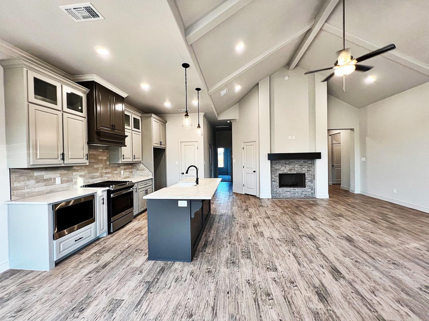 6920 17th Street Lubbock, TX 79416 - Photo 6 of 34 a large kitchen with stainless steel appliances granite countertop a stove and a wooden floors