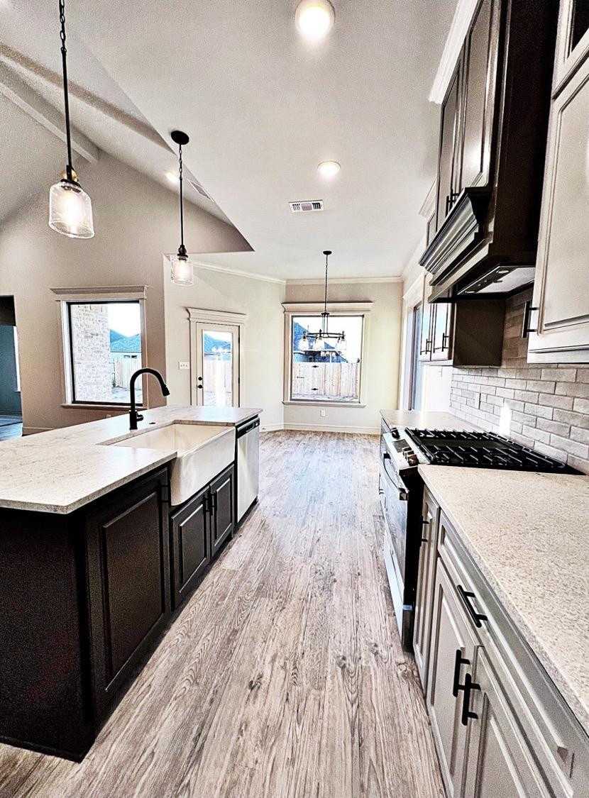 6920 17th Street Lubbock, TX 79416 - Photo 8 of 34 a large kitchen with stainless steel appliances granite countertop a sink a stove and a wooden floors