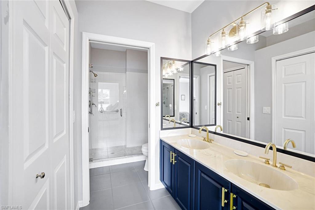 5967 Sand Wedge Lane, Unit 104 Naples, FL 34110 - Photo 12 of 41 a bathroom with a double vanity sink mirror double and shower