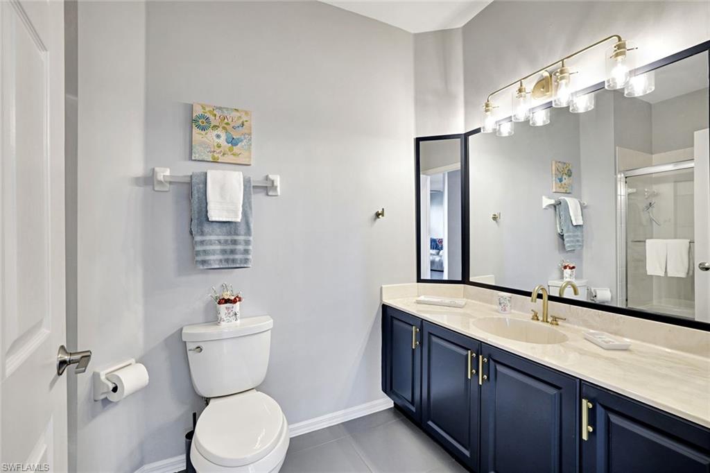 5967 Sand Wedge Lane, Unit 104 Naples, FL 34110 - Photo 15 of 41 a bathroom with a granite countertop toilet sink and mirror