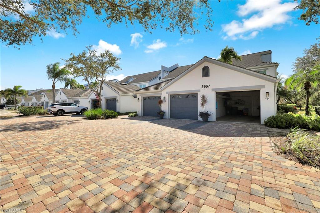 5967 Sand Wedge Lane, Unit 104 Naples, FL 34110 - Photo 25 of 41 a view of a white house with a yard and potted plants