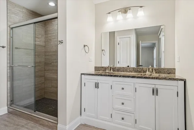 a bathroom with a granite countertop sink a mirror and shower