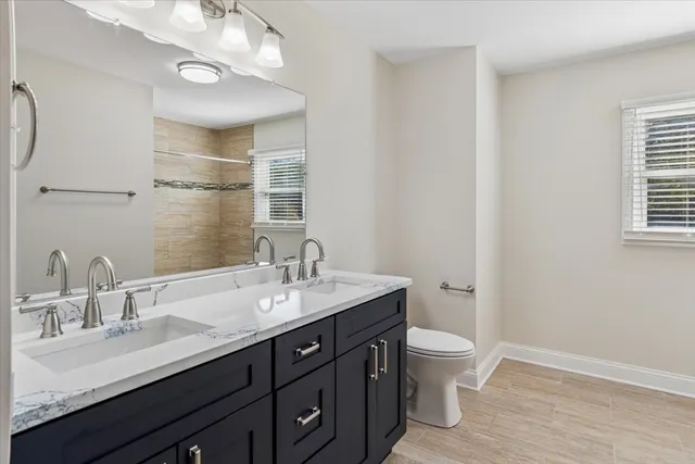 a bathroom with a double vanity sink toilet and a mirror