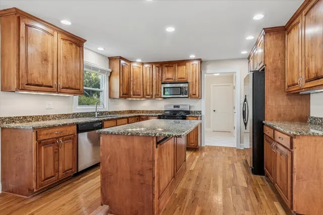 a kitchen with kitchen island granite countertop wooden cabinets a sink and a stove