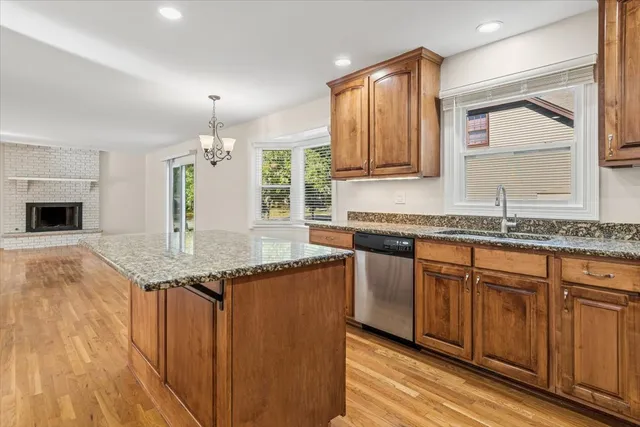 a kitchen with granite countertop kitchen island stainless steel appliances a sink stove and cabinets