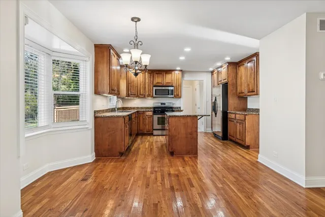 a kitchen with stainless steel appliances granite countertop a refrigerator a stove top oven a sink dishwasher and wooden floor