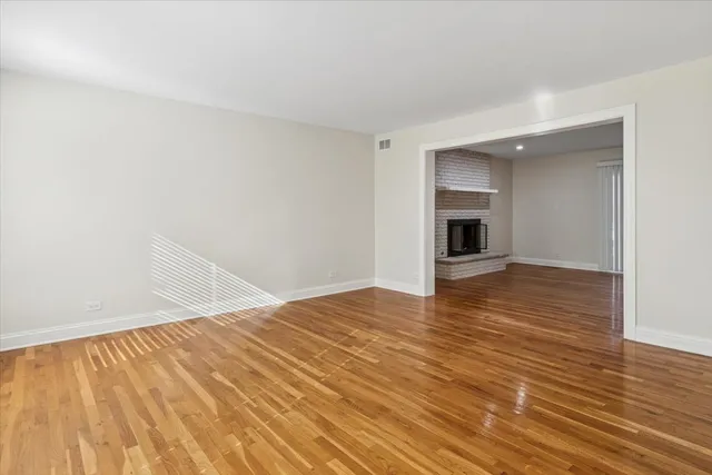 a view of empty room with wooden floor and fireplace