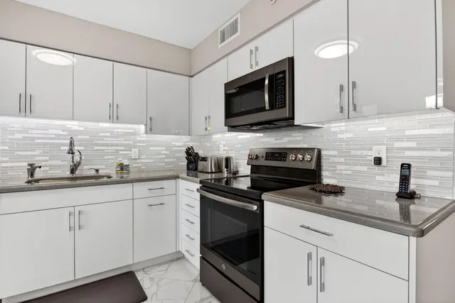 a kitchen with granite countertop white cabinets white stainless steel appliances and a sink