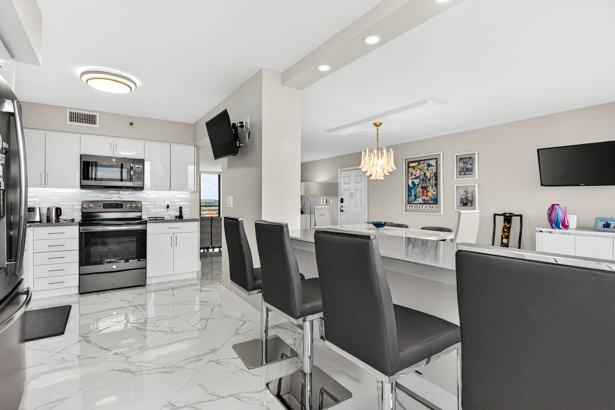7186 Promenade Drive, Unit 701 Boca Raton, FL 33433 - Photo 19 of 39 a kitchen with stainless steel appliances granite countertop a stove top oven a sink dishwasher a dining table and chairs with wooden floor