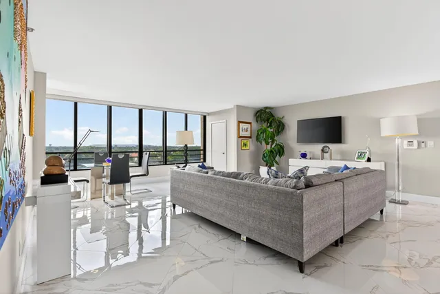 a living room with furniture large windows and flat screen tv