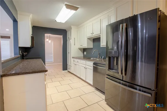 a kitchen with granite countertop a refrigerator and a sink