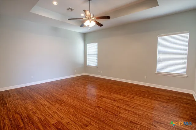 an empty room with wooden floor and windows