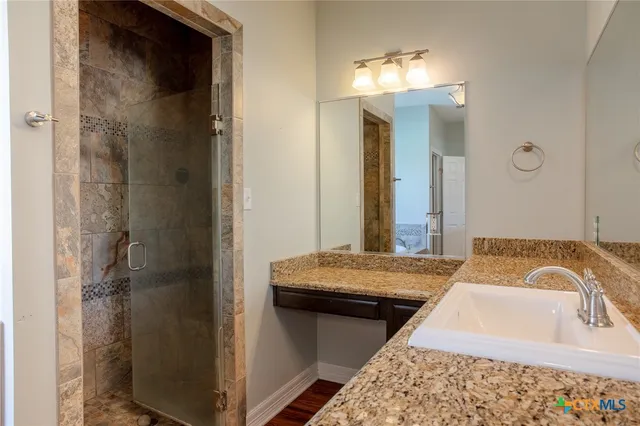 a en suite bathroom with a granite countertop sink and a mirror