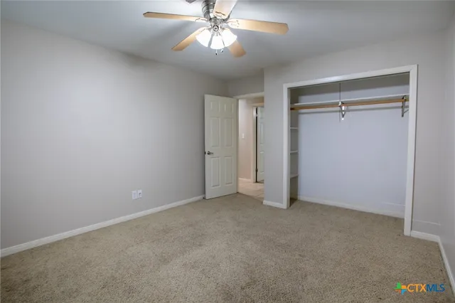 an empty room with closet and a chandelier fan